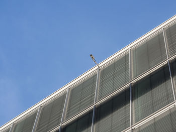 Low angle view of building with security camera against clear sky