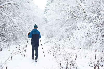 Rear view of man walking on snow covered land