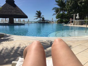 Low section of woman relaxing in swimming pool