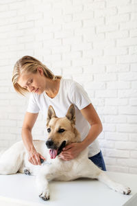 Woman with dog against wall