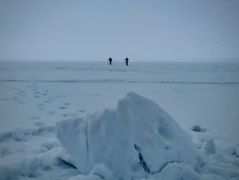 People on snow covered land against sky