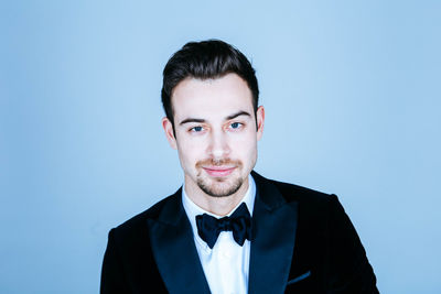 Portrait of handsome man wearing suit against blue background