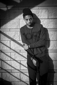 Portrait of young man standing against wall