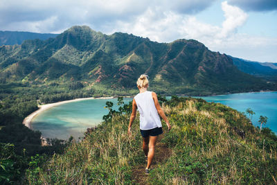 Rear view of young woman looking at lake against mountains