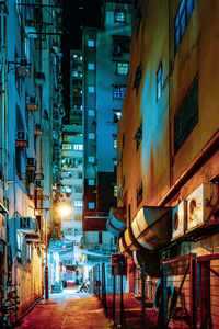 Illuminated street amidst buildings in city at night