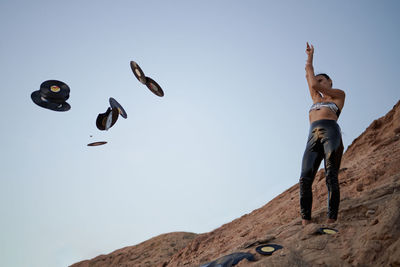 Low angle view of man standing on mountain against clear sky