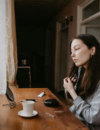 Portrait of young woman sitting on table at home