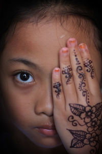 Close-up portrait of girl showing henna tattoo on hand