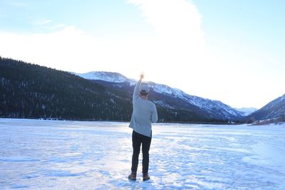 Man standing on snow covered landscape against sky