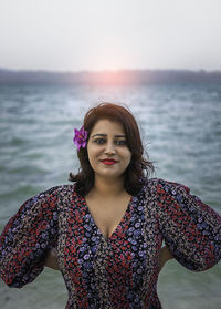 Portrait of young woman standing against sea against sky