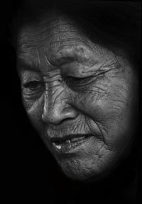 Close-up of senior woman against black background