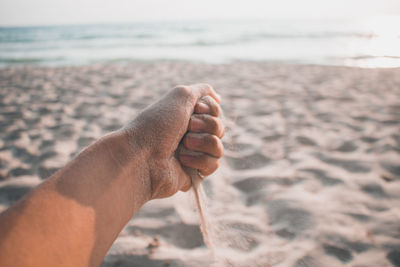 Cropped hand holding sand on beach