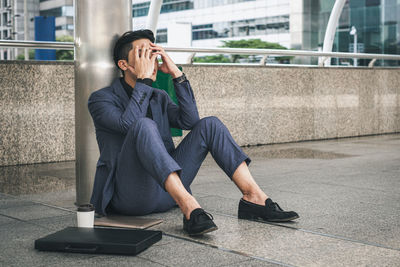 Man sitting on mobile phone in city