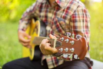 Midsection of man playing guitar