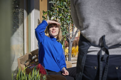 Colleague shielding eyes while looking at owner outside store on sunny day