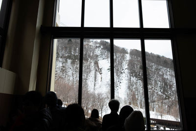 Rear view of people looking through window