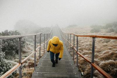 Rear view of man walking on footbridge