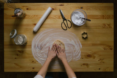 Top view of a young woman making christmas cookies on a wooden table