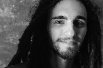 Close-up portrait of young man with dreadlocks against wall