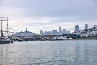 Sea by buildings in city against sky