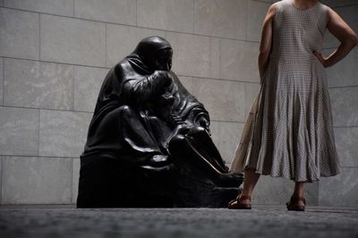 Low section of woman standing by statue in museum