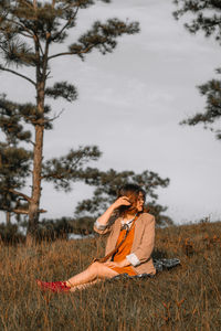 Woman sitting on land against sky