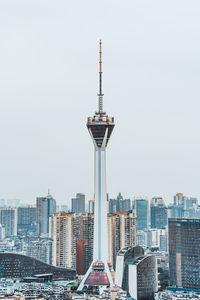 Communications tower in city against clear sky