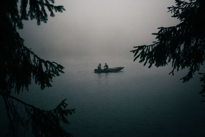 People rowing boat in lake during foggy weather