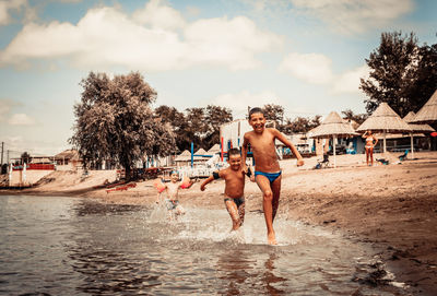 Happy boys running through the water and having fun on the beach during summer holiday.