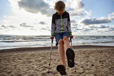 Rear view of boy on beach against sky