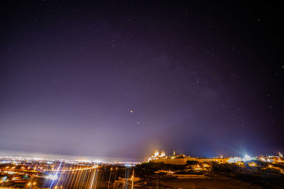 Low angle view of illuminated buildings against sky at night