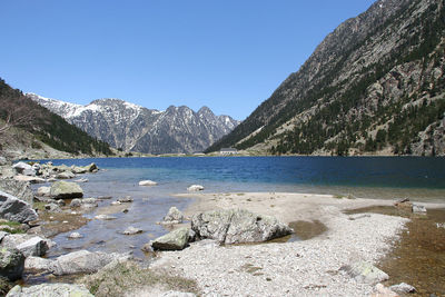 Scenic view of lake and mountains against clear blue sky