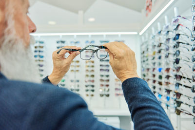 Midsection of man holding eyeglasses on display at store