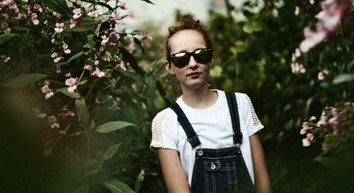 Close-up portrait of girl standing by flowers at park