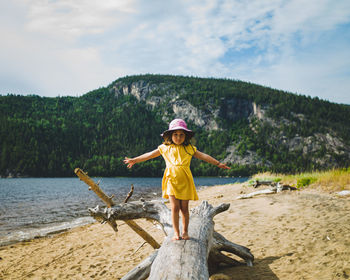 Full length of girl standing at beach against sky