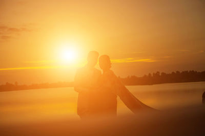 Couple kissing against orange sky during sunset
