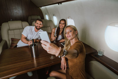 Businesswoman taking selfie while sitting in corporate jet