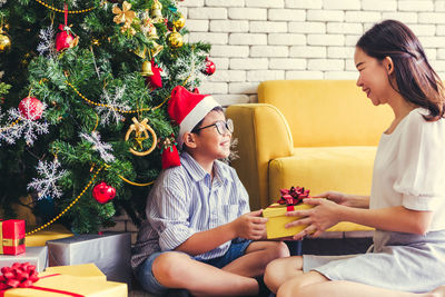 Young woman sitting by christmas tree