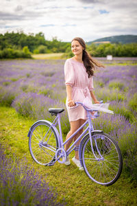 Portrait of smiling woman with bicycle on field