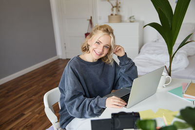 Portrait of young woman using laptop at home