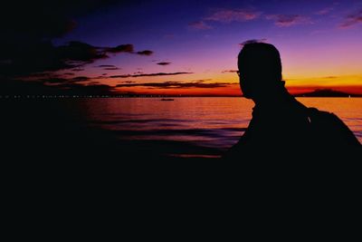 Silhouette person by sea against sky during sunset