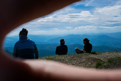 People sitting on mountain against sky