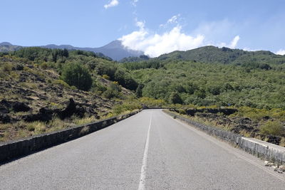 Empty road amidst trees against sky