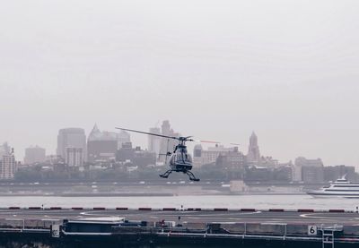 Helicopter flying in city against sky