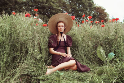 Portrait of young woman sitting on field