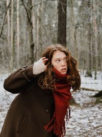 Young woman leaning while looking away in forest