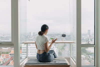 Rear view of woman sitting at balcony