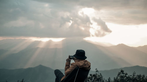 A man is taking the photo on the peak and looking at the sky explosions