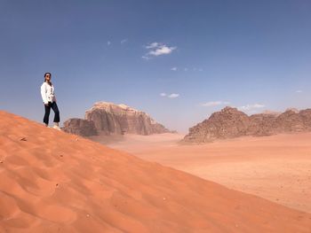 Woman standing at desert against sky