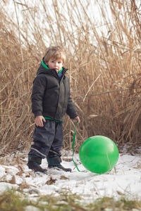 Portrait of boy with helium balloon standing on snow